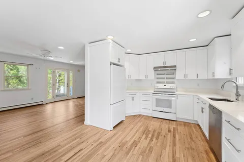 a kitchen with granite countertop a sink cabinets stainless steel appliances and a window