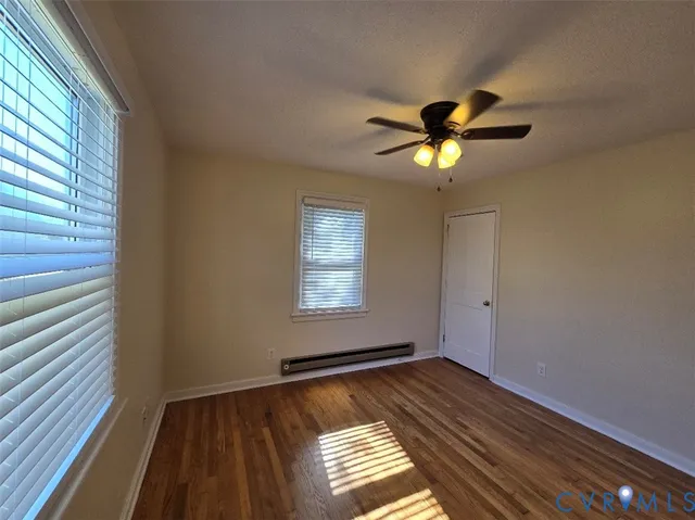 a view of an empty room with window and a chandelier fan