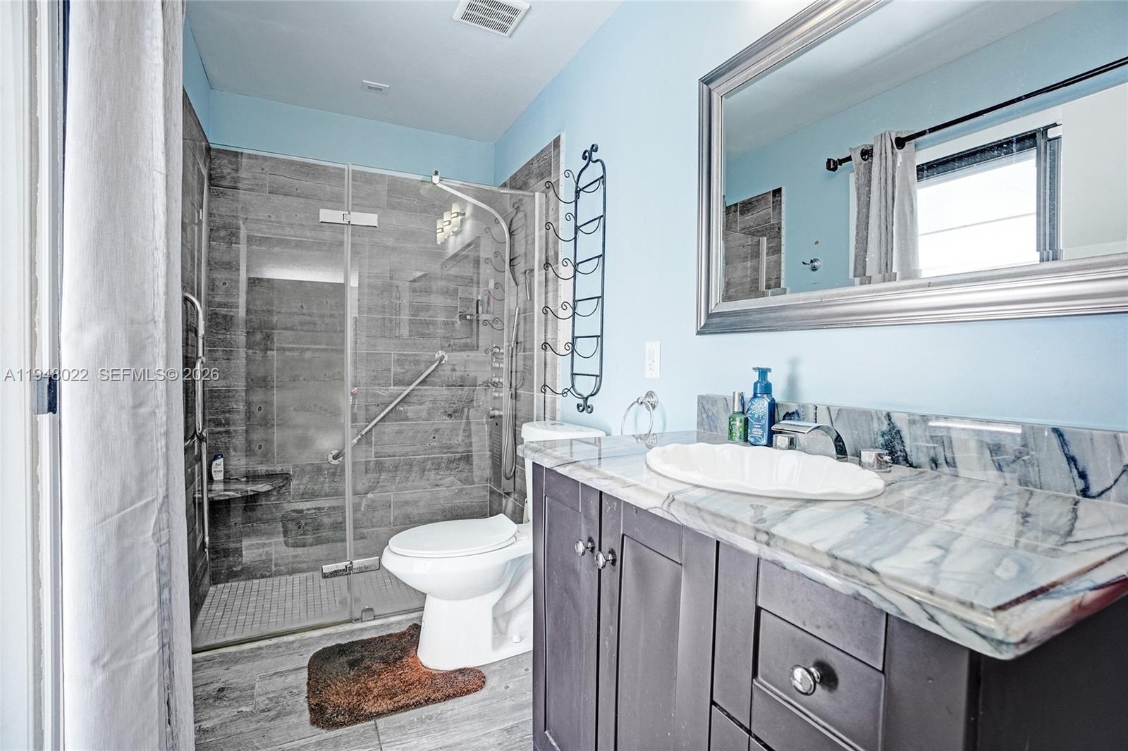 2252 Southeast Rainier Road Port St. Lucie, FL 34952 - Photo 28 of 52 a bathroom with a granite countertop sink a toilet and shower