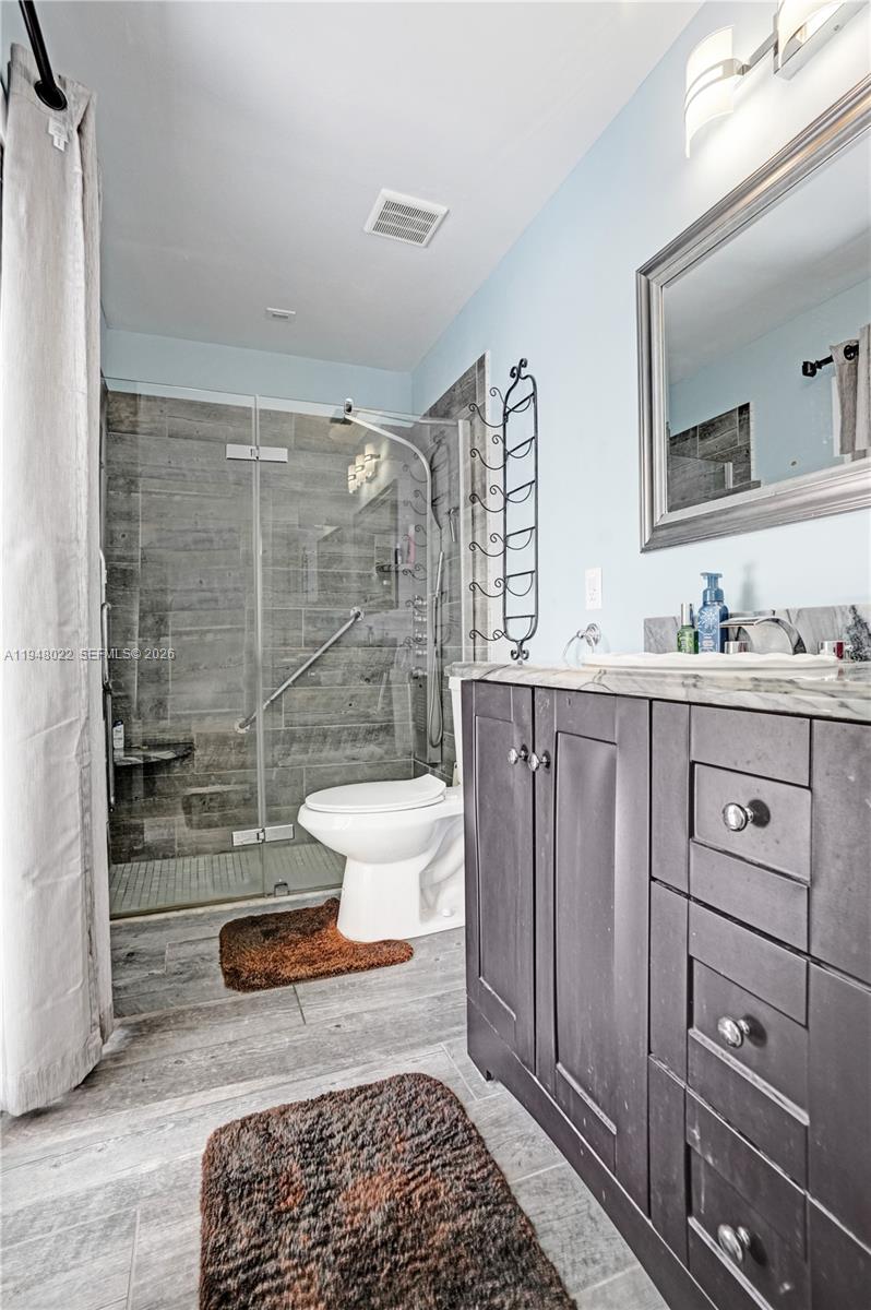 2252 Southeast Rainier Road Port St. Lucie, FL 34952 - Photo 29 of 52 a bathroom with a toilet a sink and glass door