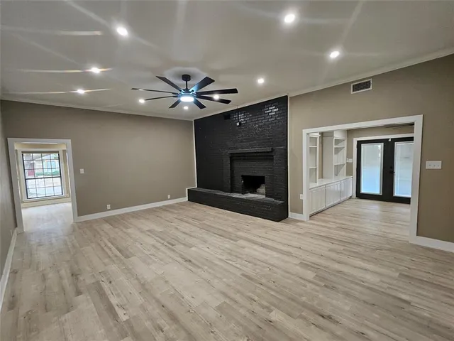 an empty room with wooden floor a fireplace and a window