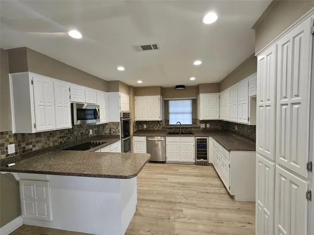 a large kitchen with stainless steel appliances granite countertop a stove a sink and a refrigerator