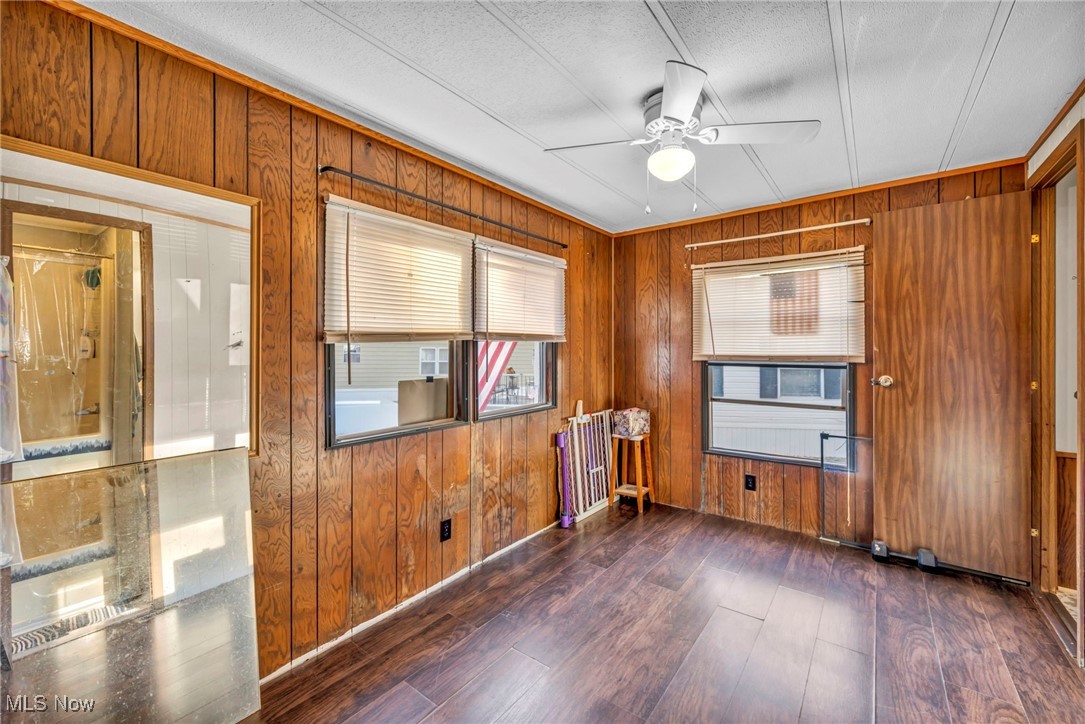 35157 Center Ridge Road, Unit 126 North Ridgeville, OH 44039 - Photo 16 of 50 Empty room featuring wooden walls, dark wood finished floors, and a ceiling fan