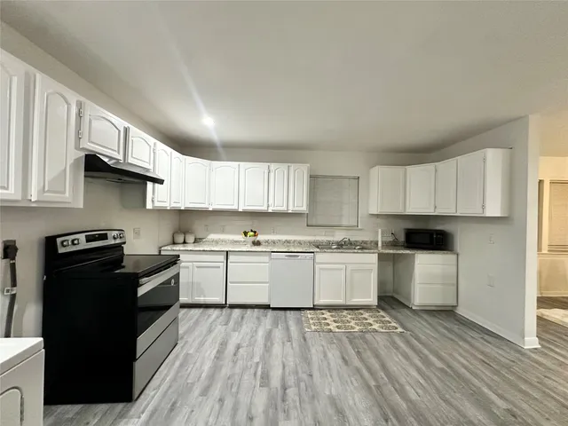 a kitchen with a sink stove top oven and cabinets