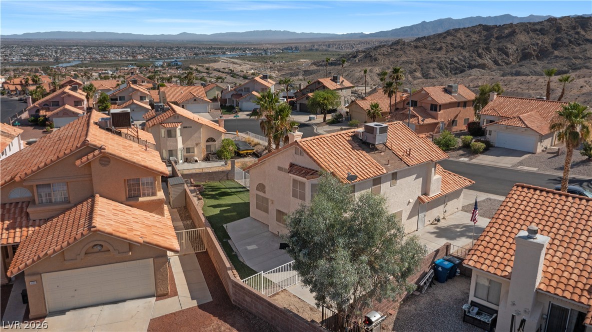 3156 Terrace View Drive Laughlin, NV 89029 - Photo 88 of 94 An aerial perspective reveals a vibrant neighborhood nestled among rugged hills, with distant water views and homes featuring tile roofs.