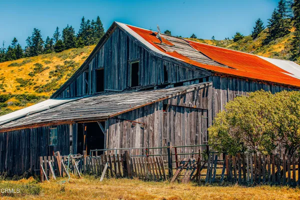 a view of a house with large trees and wooden fence