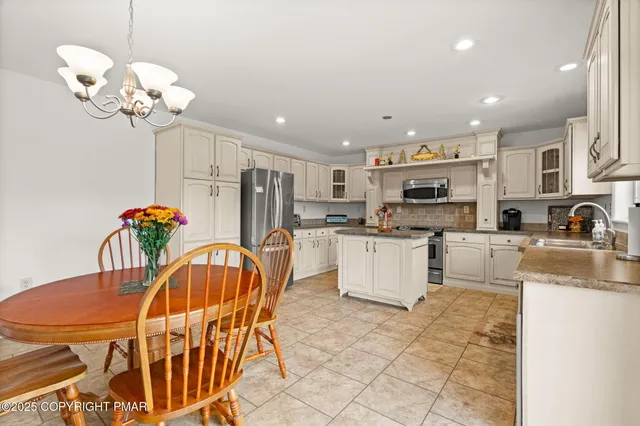 a kitchen with stainless steel appliances granite countertop a refrigerator oven a sink a stove a dining table and chairs