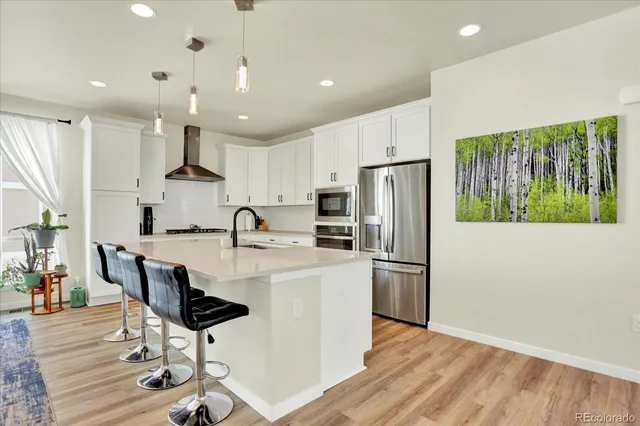 a kitchen with stainless steel appliances a refrigerator sink and wooden floor