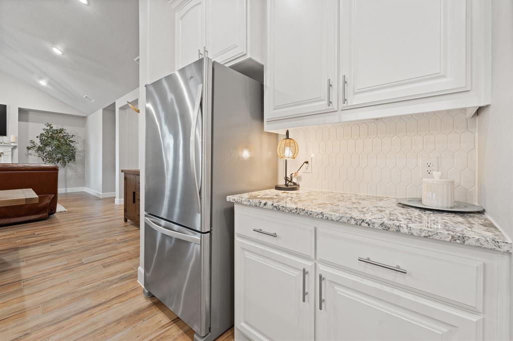 1741 River Bend Road Burleson, TX 76028 - Photo 14 of 33 Kitchen with white cabinetry, freestanding refrigerator, vaulted ceiling, light wood-style floors, and backsplash