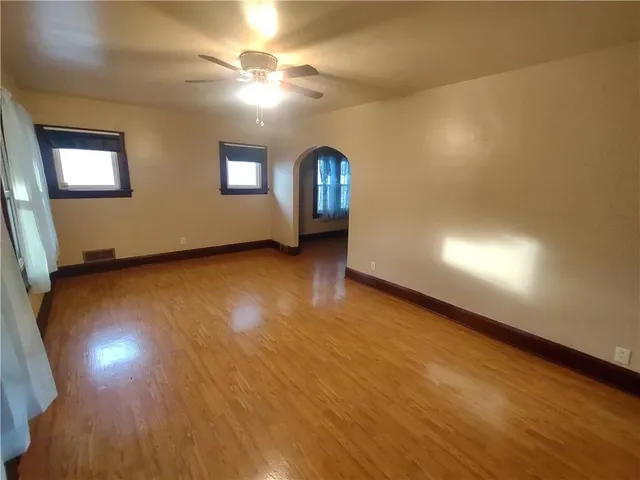 a view of an empty room with window and wooden floor