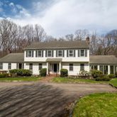 a front view of a house with a garden and trees