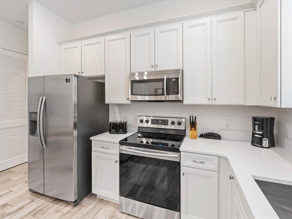 8092 Knee Deep Road Kissimmee, FL 34747 - Photo 8 of 26 a kitchen with stainless steel appliances white cabinets and a refrigerator