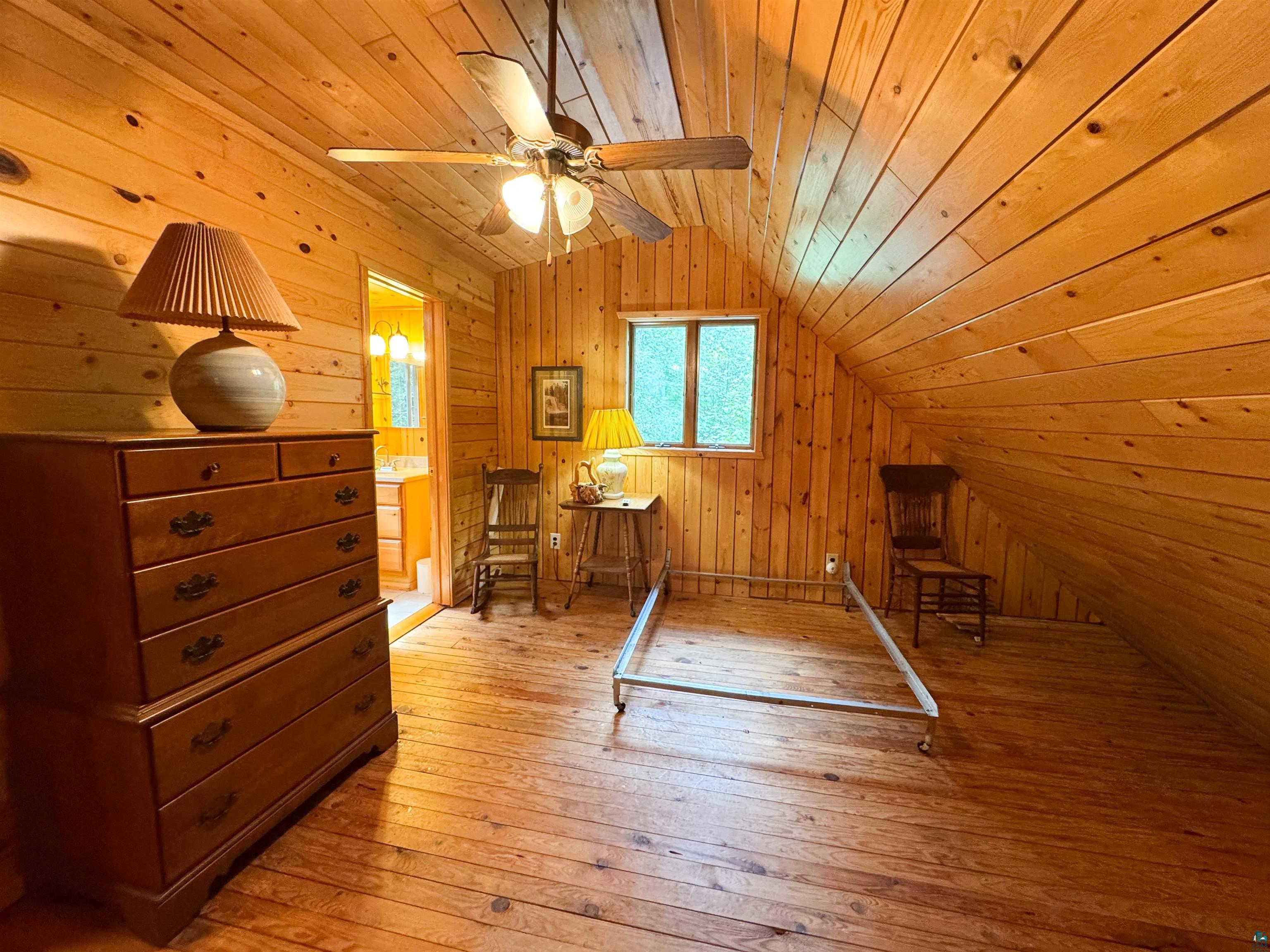 465 South Gunflint Lake Road Grand Marais, MN 55604 - Photo 37 of 46 Room featuring natural wood plank walls, matching wood-finish flooring, and a sloped ceiling
