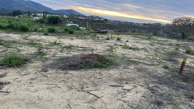 a view of a dry yard with wooden fence