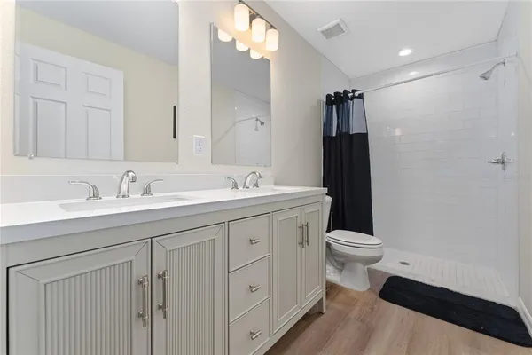 a bathroom with a sink a toilet a mirror and shower