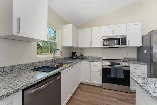 a kitchen with stainless steel appliances granite countertop a stove a sink and a microwave
