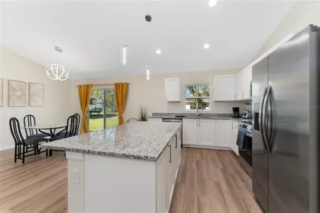 a kitchen with granite countertop kitchen island wooden floor center island and stainless steel appliances