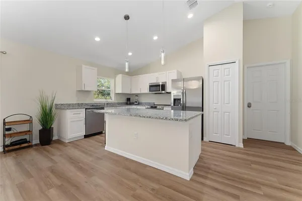 a kitchen with kitchen island white cabinets and stainless steel appliances