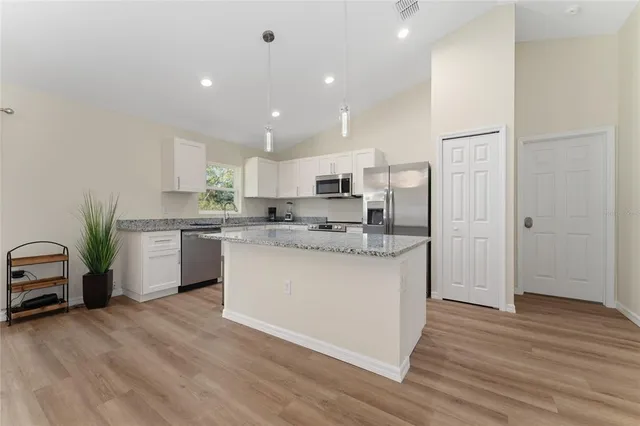 a kitchen with kitchen island white cabinets and stainless steel appliances