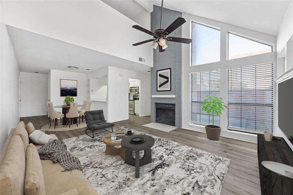 18240 Midway Road, Unit 402 Dallas, TX 75287 - Photo 3 of 29 Spacious living area featuring vaulted ceilings, wood-finish flooring, a brick fireplace, and large windows with blinds
