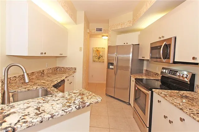 a kitchen with stainless steel appliances granite countertop a refrigerator and a stove top oven