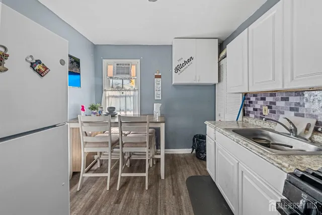 a kitchen with a refrigerator a stove a sink dishwasher and white cabinets with wooden floor