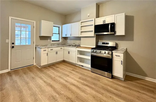 a kitchen with stainless steel appliances granite countertop a stove top oven a sink dishwasher and a microwave oven with cabinets