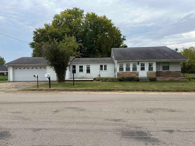 a front view of a house with a garden and trees