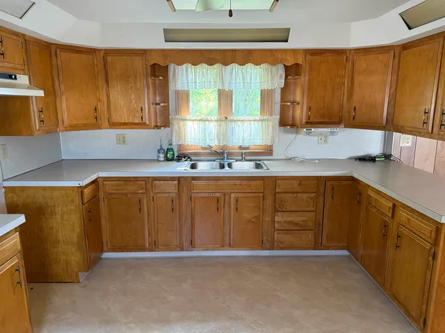 a kitchen with stainless steel appliances granite countertop a sink window and cabinets