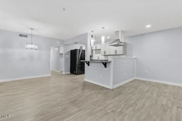 a view of a kitchen with refrigerator and wooden floor