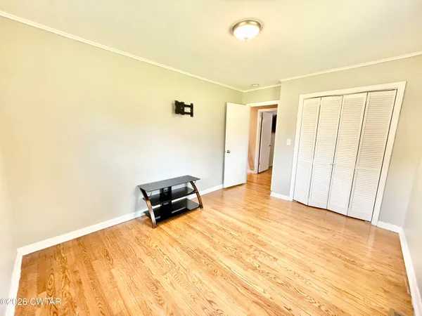 a view of an empty room with a window and wooden floor