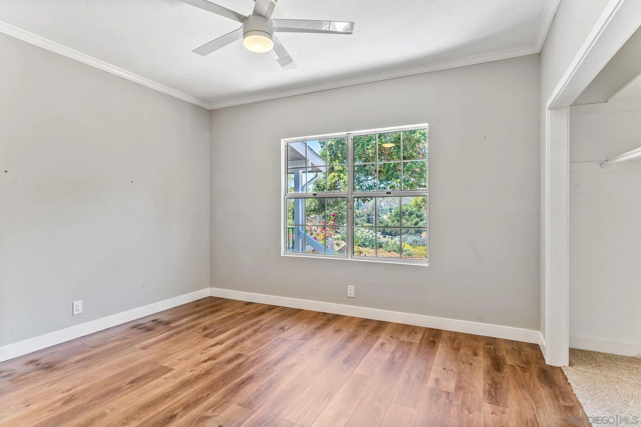 29575 Costalota Road Valley Center, CA 92082 - Photo 23 of 39 an empty room with wooden floor chandelier fan and windows