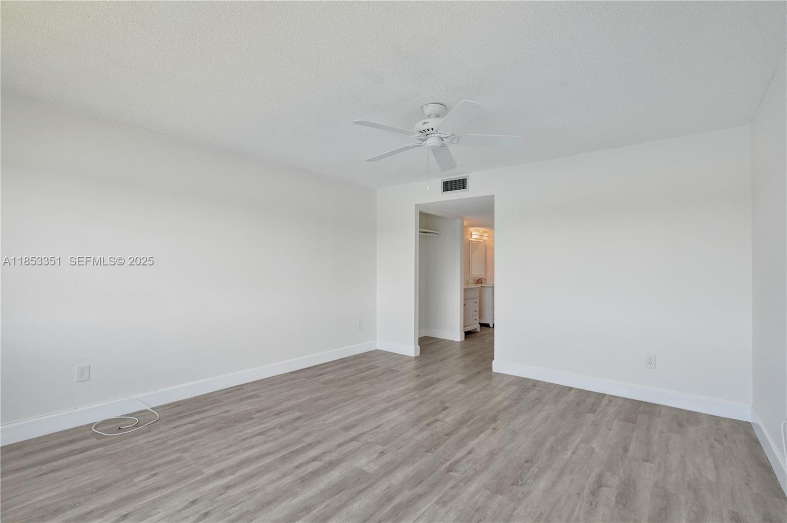 873 Northeast 195th Street, Unit 309 North Miami Beach, FL 33179 - Photo 15 of 35 an empty room with wooden floor and ceiling fan