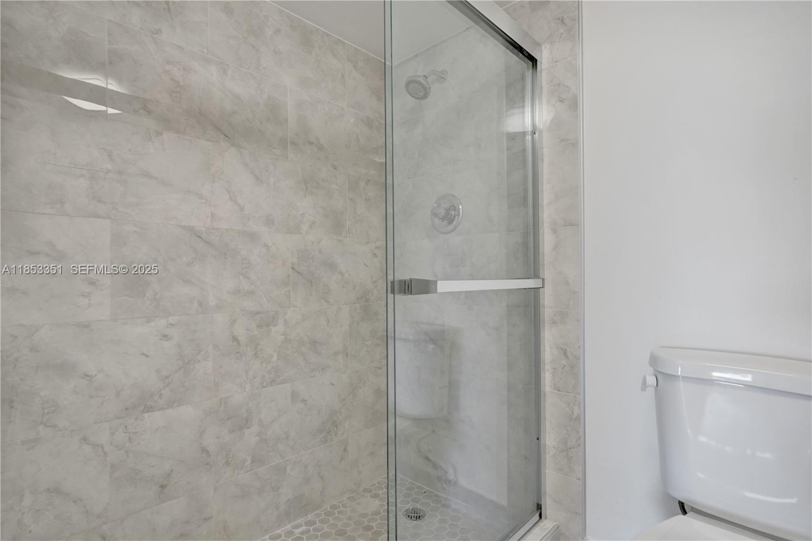 873 Northeast 195th Street, Unit 309 North Miami Beach, FL 33179 - Photo 16 of 35 a bathroom with a glass shower door