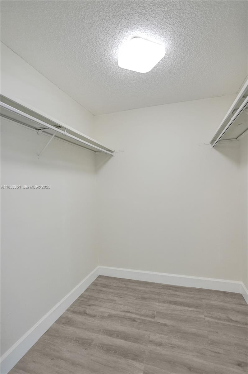 873 Northeast 195th Street, Unit 309 North Miami Beach, FL 33179 - Photo 19 of 35 a view of an empty room with wooden floor and a window