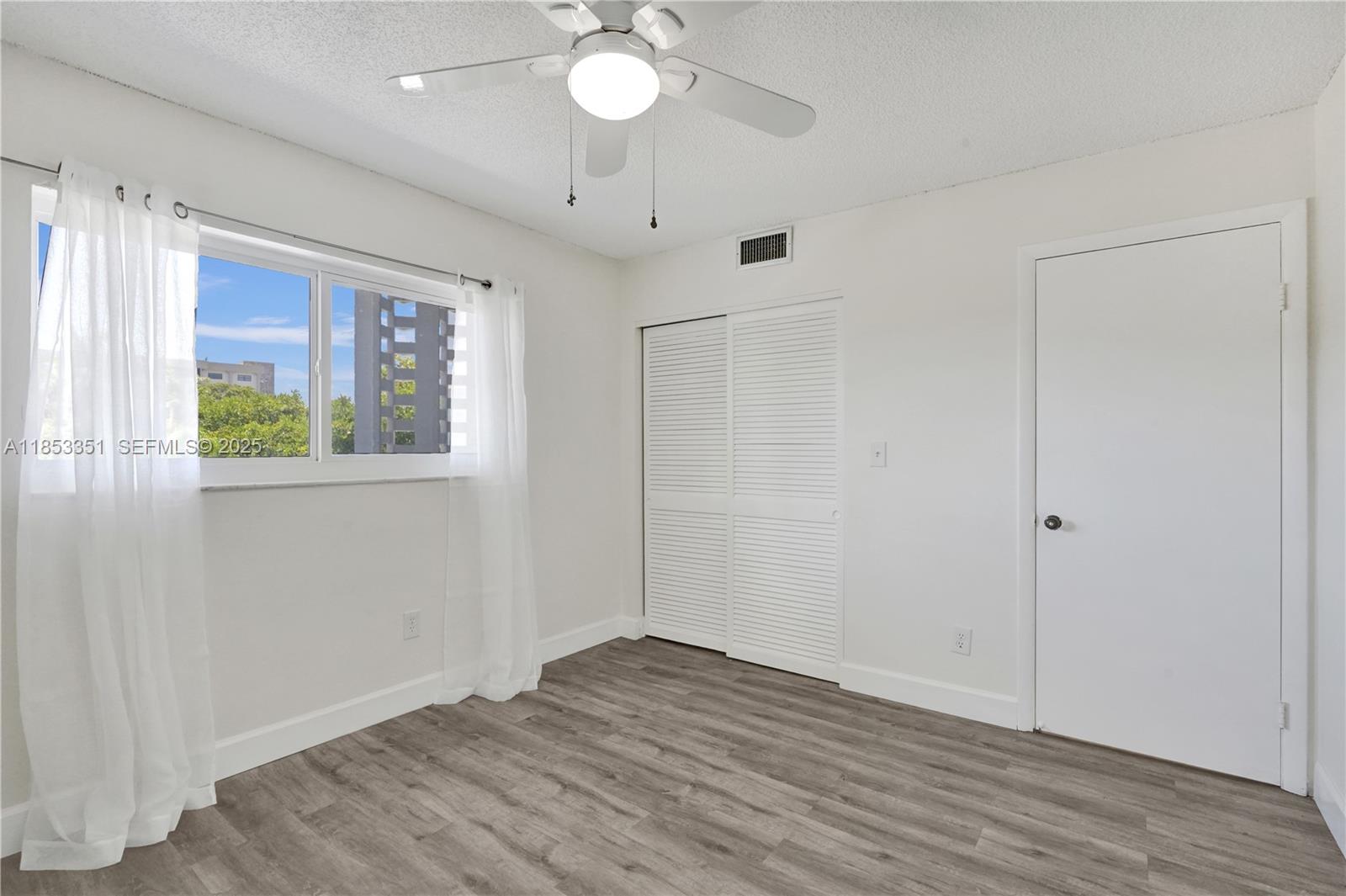 873 Northeast 195th Street, Unit 309 North Miami Beach, FL 33179 - Photo 21 of 35 an empty room with wooden floor and windows