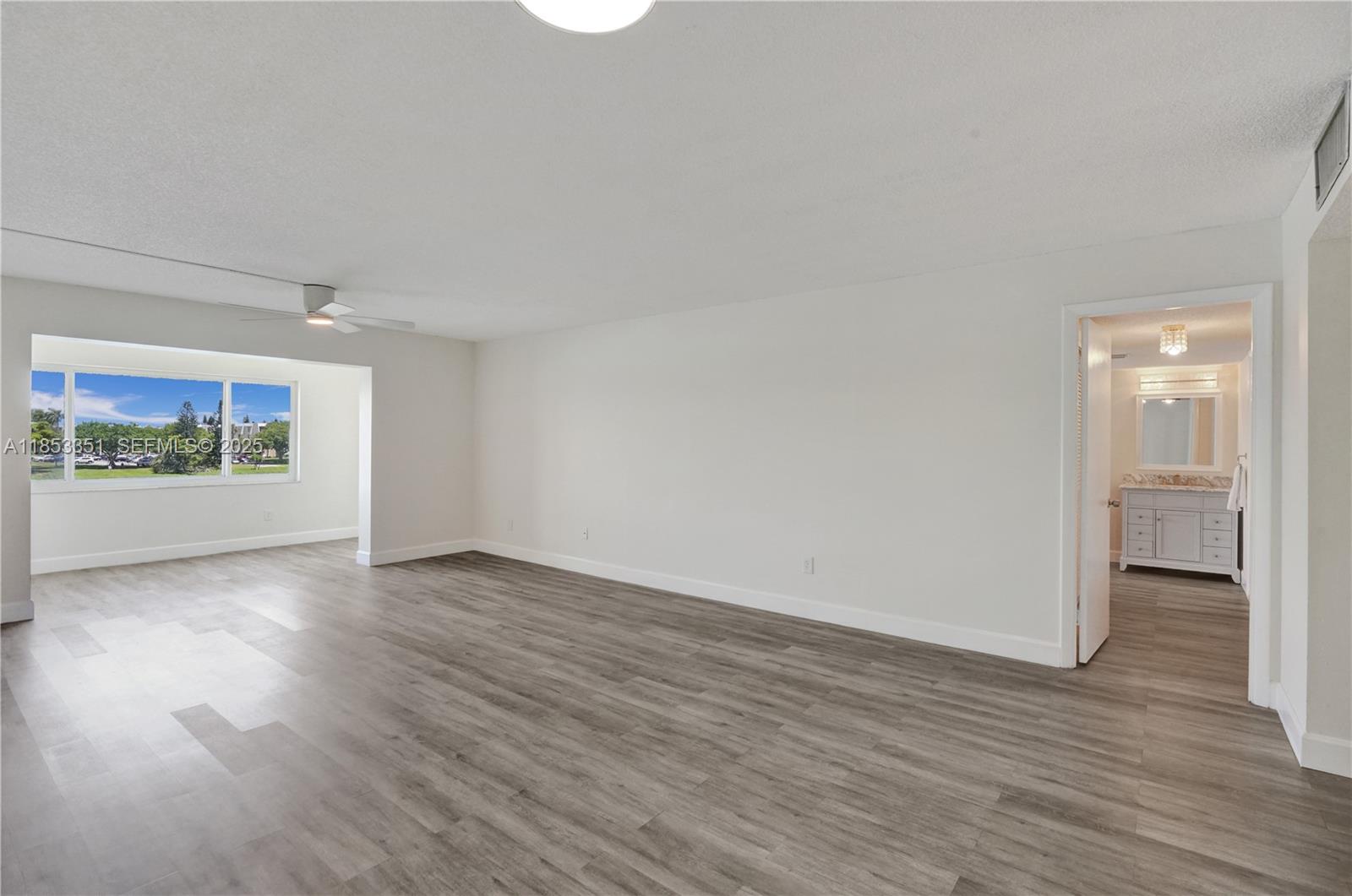 873 Northeast 195th Street, Unit 309 North Miami Beach, FL 33179 - Photo 4 of 35 a view of an empty room with wooden floor and a window