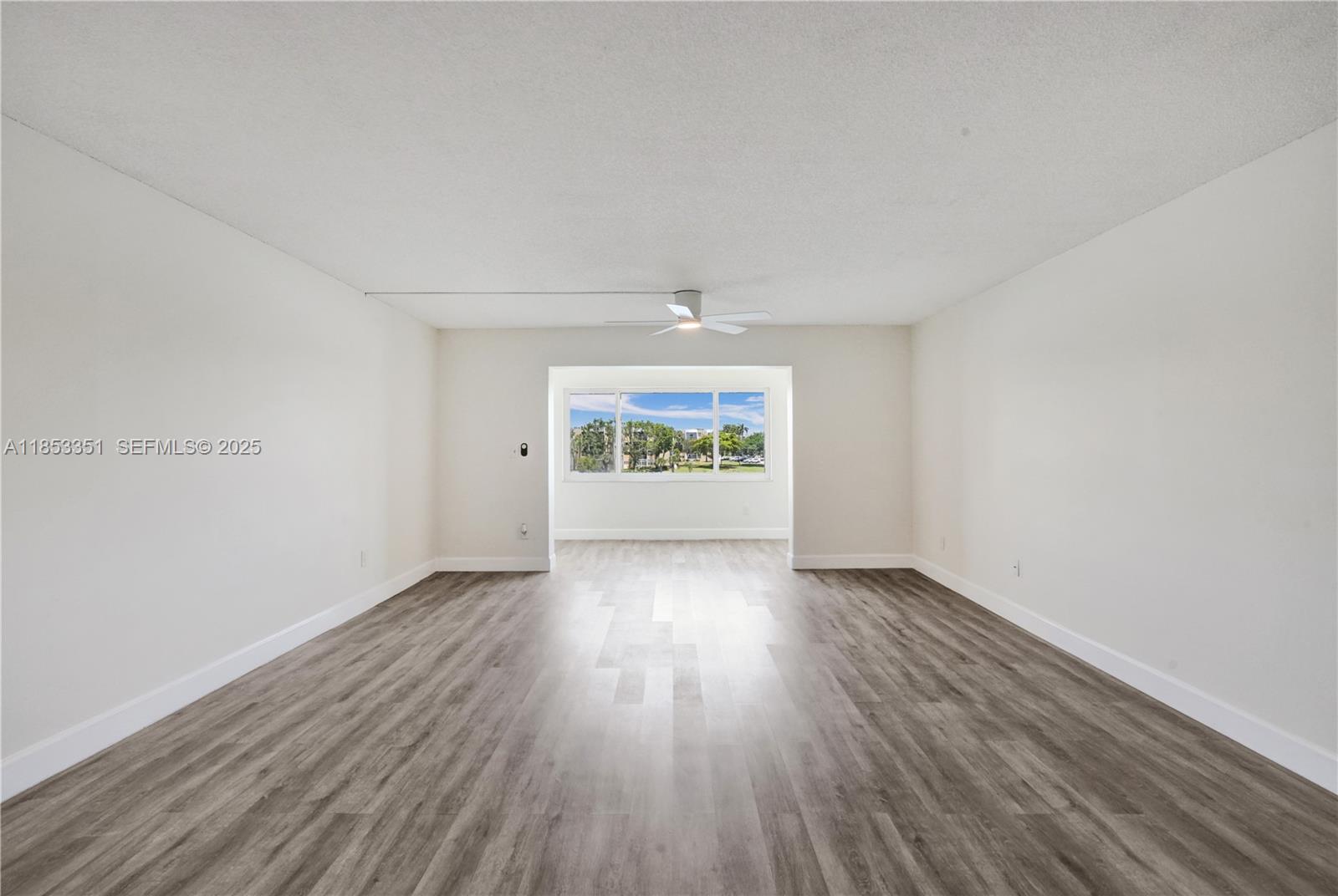 873 Northeast 195th Street, Unit 309 North Miami Beach, FL 33179 - Photo 5 of 35 an empty room with wooden floor and windows