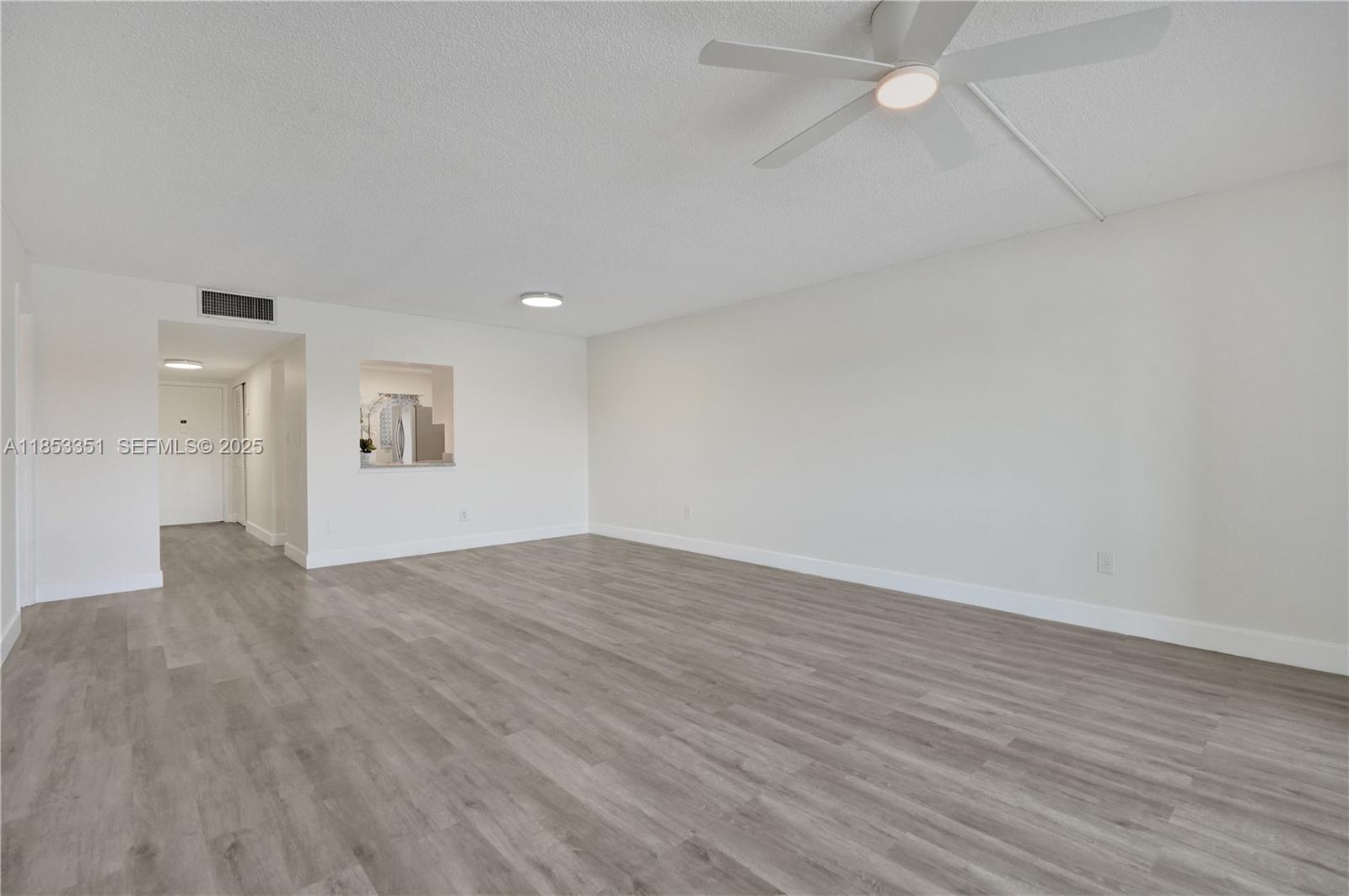 873 Northeast 195th Street, Unit 309 North Miami Beach, FL 33179 - Photo 6 of 35 a view of an empty room with wooden floor and a window