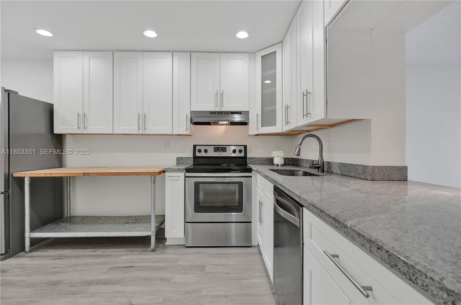 873 Northeast 195th Street, Unit 309 North Miami Beach, FL 33179 - Photo 9 of 35 a kitchen with granite countertop white cabinets and stainless steel appliances