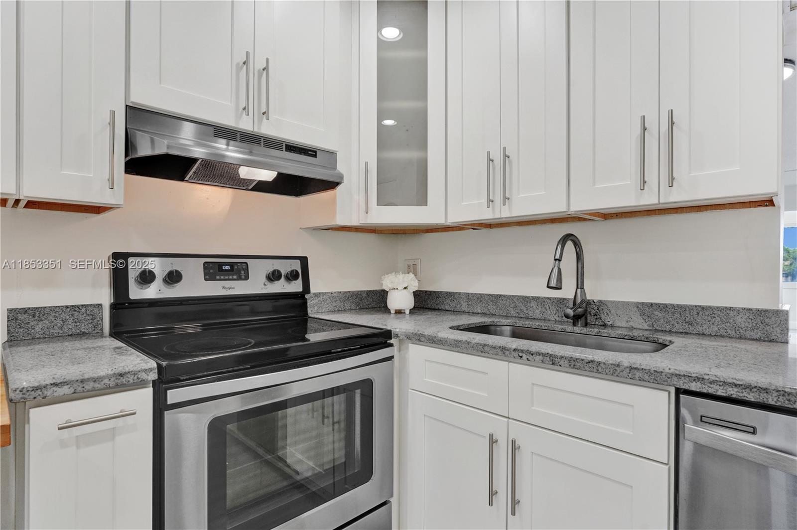 873 Northeast 195th Street, Unit 309 North Miami Beach, FL 33179 - Photo 10 of 35 a kitchen with granite countertop white cabinets and a stove top oven