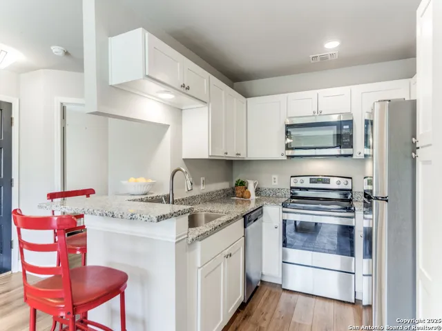 a kitchen with stainless steel appliances a white stove top oven a sink dishwasher and a refrigerator