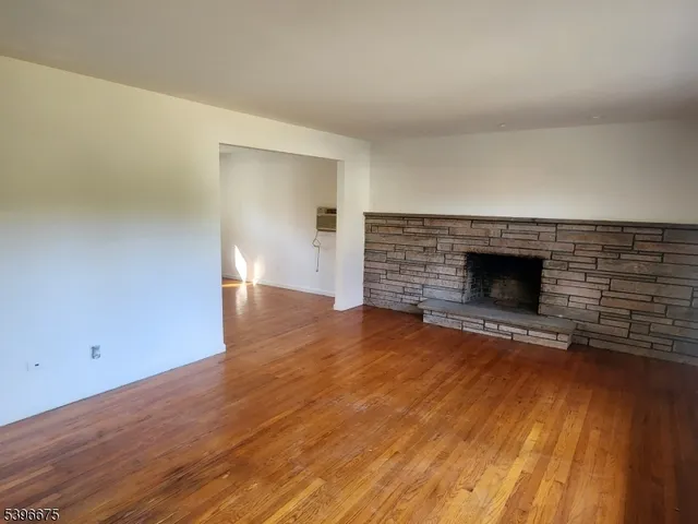 a view of empty room with wooden floor and fireplace