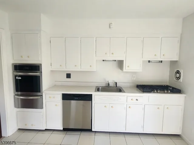 a kitchen with granite countertop white cabinets and stainless steel appliances