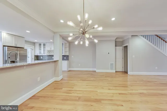 a view of an empty room with kitchen and window