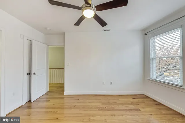 a view of an empty room with window and wooden floor