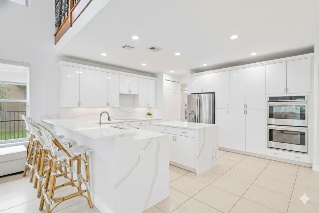 19219 North Creekshore Court Boca Raton, FL 33498 - Photo 14 of 73 a kitchen with stainless steel appliances kitchen island granite countertop a sink and cabinets