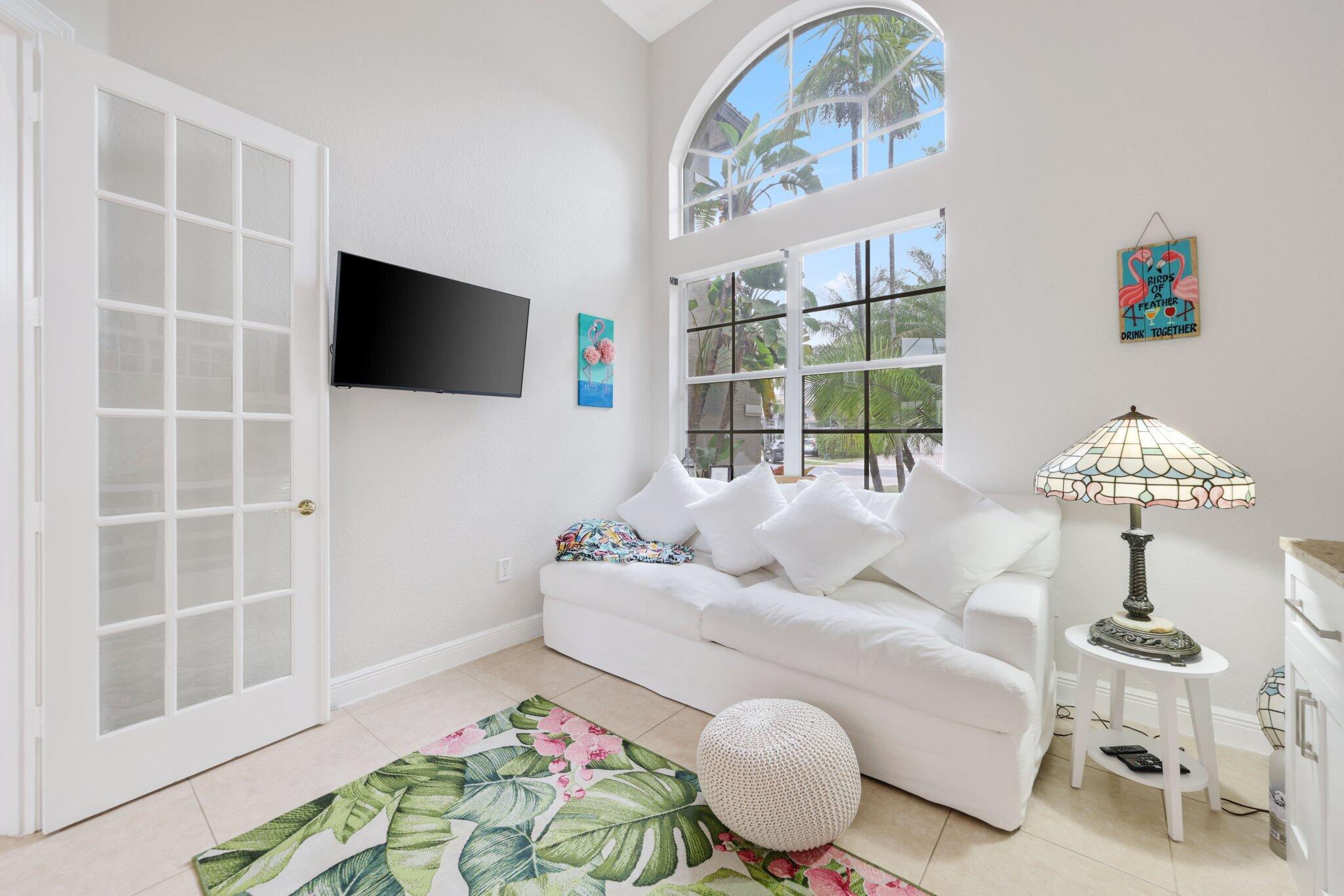 19219 North Creekshore Court Boca Raton, FL 33498 - Photo 40 of 73 a living room with furniture a flat screen tv and a floor to ceiling window