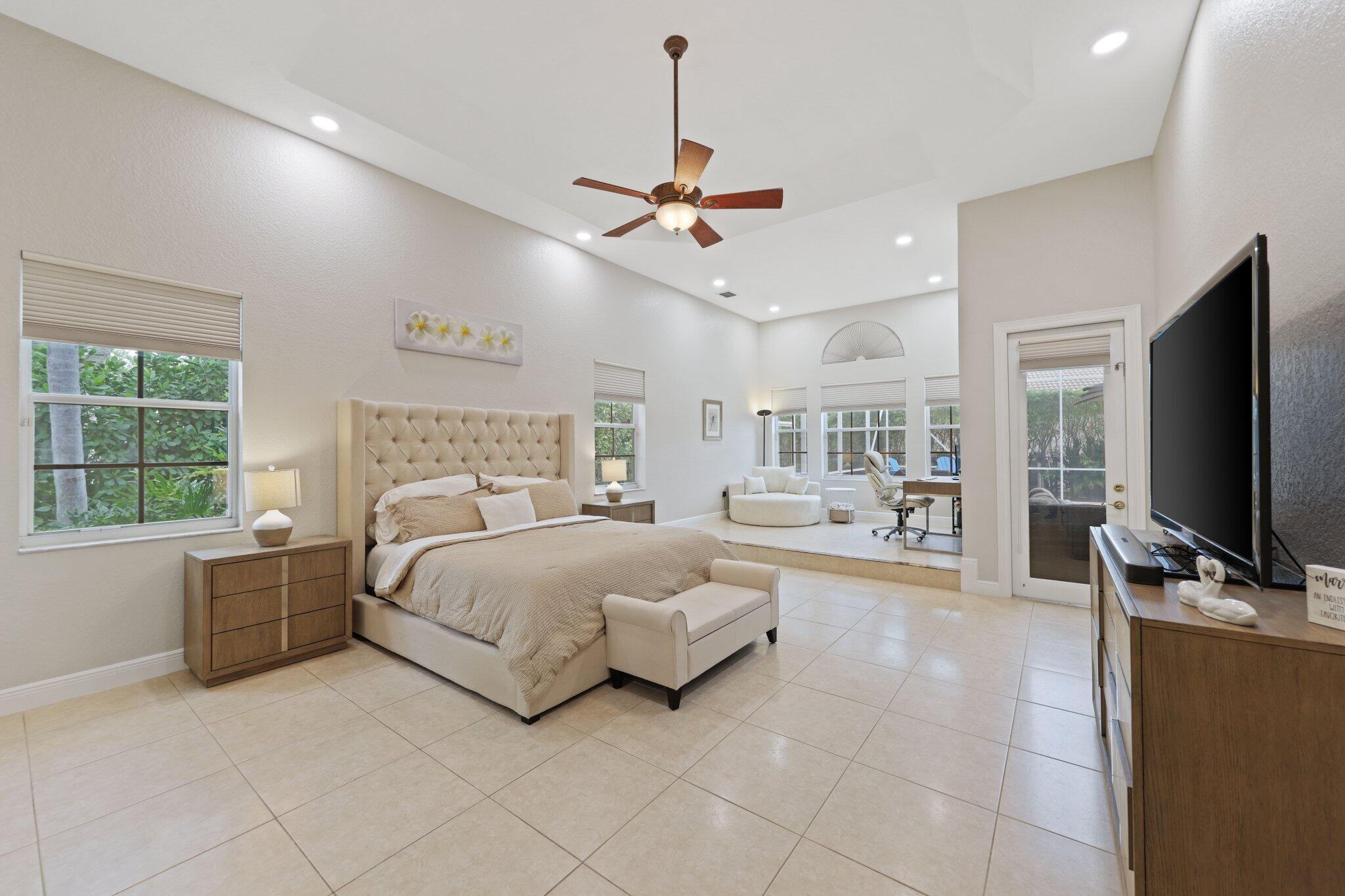 19219 North Creekshore Court Boca Raton, FL 33498 - Photo 46 of 73 a spacious bedroom with a bed flat screen tv and a large window