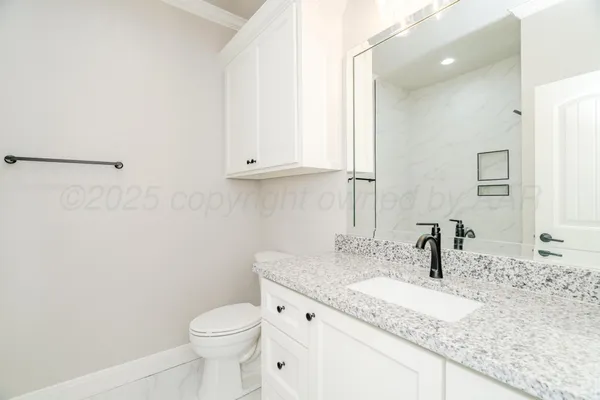 a bathroom with a granite countertop sink a toilet and a mirror